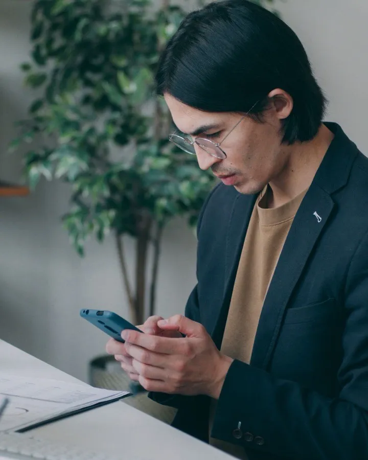Un jeune homme au bureau, consultant son téléphone